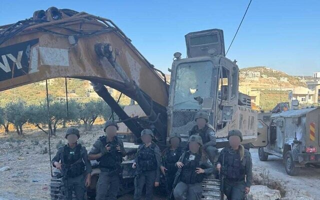 Border troops pose with an excavator suspected of being stolen from the army, in a picture distributed on July 17, 2025. (Police spokesperson)