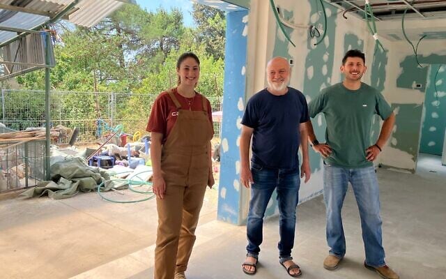 Ido Shelem, center, financial manager of Kibbutz Manara, stands with Almog Levanon, left, and Uriel Weintrub, founders of Shuvu Manara, in the nursery school destroyed by Hezbollah rockets during the Israel-Hezbollah conflict and is now being rebuilt. (Diana Bletter/Times of Israel)