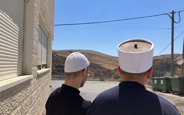 Two men who crossed into Syria and returned to Israel stand in Majdal Shams looking across into Syria on July 17, 2025. (Diana Bletter/Times of Israel)