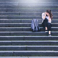 Illustrative: An upset student sits in a school yard (iStock by Getty Images)