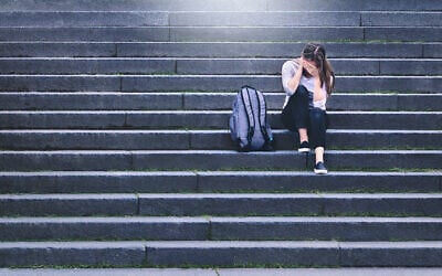 Illustrative: An upset student sits in a school yard (iStock by Getty Images)