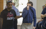 American-Israeli teenager Michael Kadar (R), accused of making dozens of antisemitic bomb threats in the United States and elsewhere, is escorted by guards as he leaves a Rishon Lezion courtroom on March 23, 2017. (Photo by JACK GUEZ / AFP)