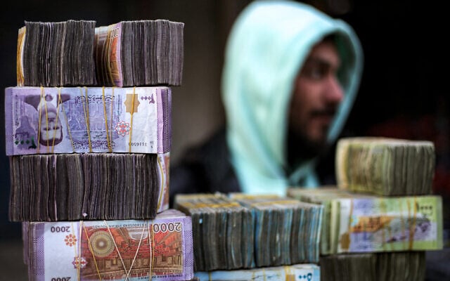 File: Stacks of Syrian pound banknotes are piled on top of each other at a currency trader's stall at a market in the city of Manbij in Syria's northern Aleppo province on January 4, 2025. (Aaref WATAD / AFP) File: Stacks of Syrian pound banknotes are piled on top of each other at a currency trader's stall at a market in the city of Manbij in Syria's northern Aleppo province on January 4, 2025. (Aaref WATAD / AFP)