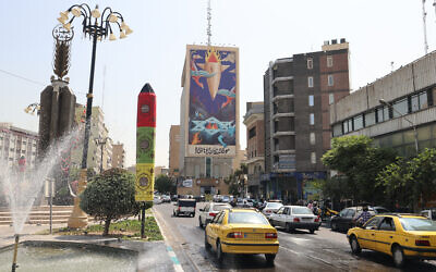Traffic flows past a huge billboard bearing a painting of a missile falling on Israel with the slogan in Farsi: "The missile has fallen amidst the demons," on a main road in central Tehran on July 16, 2025.(Atta Kenare/AFP)