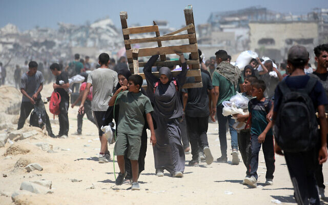 A Palestinian woman carries a wooden pallet as she returns from an area in which aid trucks entered Gaza through the Zikim crossing point, in Jabalia in the northern Gaza Strip on August 1, 2025. The UN human rights office said on August 1 that 1,373 Palestinians have been killed while waiting for aid in the shortage-stricken Gaza Strip since late May, most of them by the Israeli military. (Photo by Bashar TALEB / AFP)