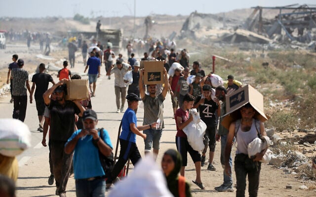Palestinians leave a food distribution point run by the US and Israeli-backed Gaza Humanitarian Foundation with bags and boxes, near the Netzarim corridor in the central Gaza Strip, on August 3, 2025. (Eyad BABA / AFP)
