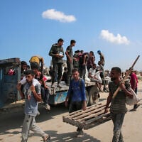 Displaced Palestinians sit on a trailer with bags of humanitarian aid they received at a distribution center run by the US and Israeli-backed Gaza Humanitarian Foundation (GHF) at the so-called "Netzarim corridor" in the central Gaza Strip on August 4, 2025.(AFP)
