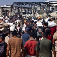 Displaced Palestinians carry bags of humanitarian aid they received at a distribution center run by the US and Israeli-backed Gaza Humanitarian Foundation (GHF) in the central Gaza Strip on August 4, 2025. (AFP)