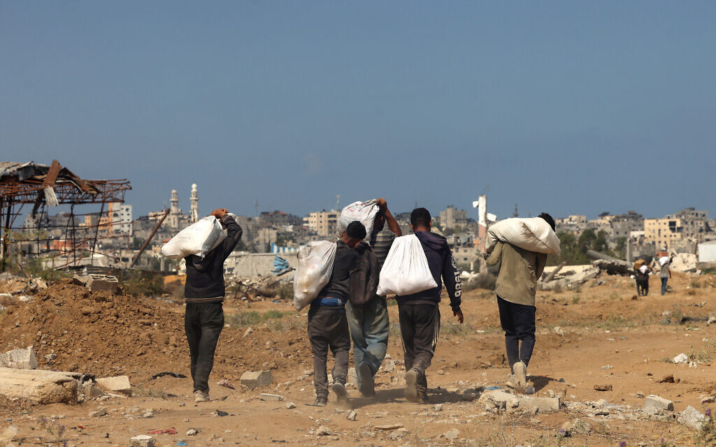 Displaced Palestinians carry bags of humanitarian aid they received at a distribution centre run by the US and Israeli-backed Gaza Humanitarian Foundation (GHF) at the so-called "Netzarim corridor" in the central Gaza Strip on August 4, 2025. Aid agencies have warned that Gaza's population is facing a catastrophic famine, triggered by Israeli restrictions on aid. (Photo by AFP) Displaced Palestinians carry bags of humanitarian aid they received at a distribution centre run by the US and Israeli-backed Gaza Humanitarian Foundation (GHF) at the so-called "Netzarim corridor" in the central Gaza Strip on August 4, 2025. Aid agencies have warned that Gaza's population is facing a catastrophic famine, triggered by Israeli restrictions on aid. (Photo by AFP)