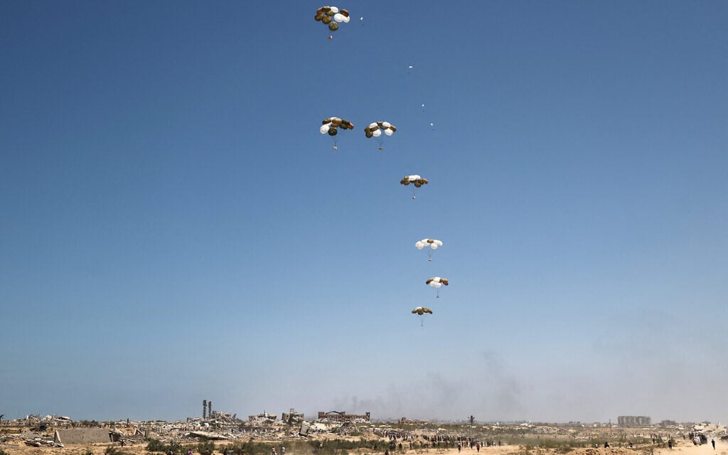 Palestinians rush to the site where parachuted aid packages are landing in the Nuseirat area in the central Gaza Strip during an airdrop on August 6, 2025. (Eyad BABA / AFP)