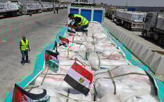 Volunteers arrange parcels as trucks loaded with humanitarian aid await permission on the Egyptian side of the Rafah crossing with the Gaza Strip, to enter the besieged Palestinians territory on August 6, 2025. (AFP)