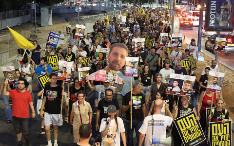 Relatives of Israeli hostages and demonstrators raise pictures and placards during an anti-government protest outside Defense Ministry headquarters in Tel Aviv on August 6, 2025. (JACK GUEZ / AFP)
