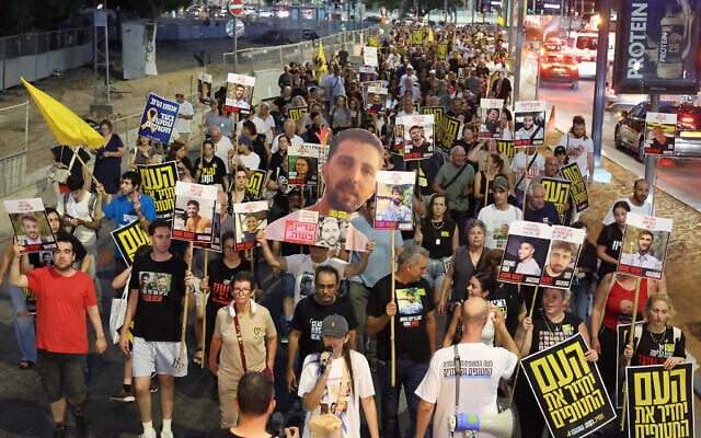 Relatives of Israeli hostages and demonstrators raise pictures and placards during an anti-government protest outside Defense Ministry headquarters in Tel Aviv on August 6, 2025. (JACK GUEZ / AFP)