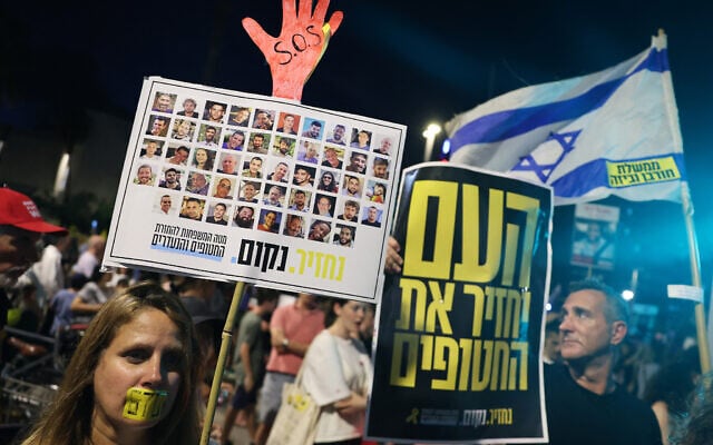 Demonstrators raise placards during an anti-government protest calling for the release hostages from the Gaza Strip, outside the IDF headquarters in Tel Aviv on August 6, 2025. (JACK GUEZ / AFP)