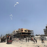 Palestinians run as a military aircraft drops parcels humanitarian aid in Jabalia in the northern Gaza Strip, on August 9, 2025. (Bashar TALEB / AFP)
