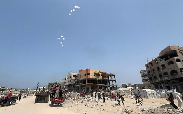 Palestinians run as a military aircraft drops parcels humanitarian aid in Jabalia in the northern Gaza Strip, on August 9, 2025. (Bashar TALEB / AFP)