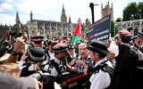 Police officers remonstrate with a protester during a "Lift The Ban" demonstration in support of the proscribed group Palestine Action, calling for the recently imposed ban to be lifted, in Parliament Square, central London, on August 9, 2025. (HENRY NICHOLLS / AFP)
