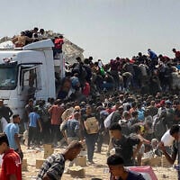 Displaced Palestinians carry food parcels as they raid trucks carrying humanitarian aid in Khan Younis, in the southern Gaza Strip on August 9, 2025. (AFP)