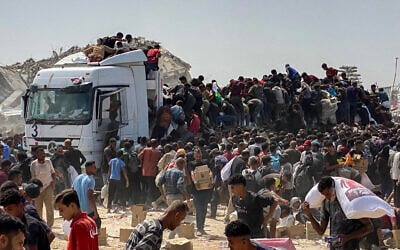 Displaced Palestinians carry food parcels as they raid trucks carrying humanitarian aid in Khan Younis, in the southern Gaza Strip on August 9, 2025. (AFP)