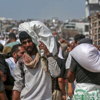 Displaced Palestinians carry food parcels as they raid trucks carrying humanitarian aid in Khan Younis, in the southern Gaza Strip on August 9, 2025. (AFP)