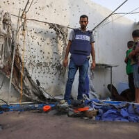 Palestinian children and a journalist examine the destroyed Al Jazeera tent at Al-Shifa Hospital in Gaza City on August 11, 2025, following an overnight strike by the IDF. (Bashar Taleb / AFP)