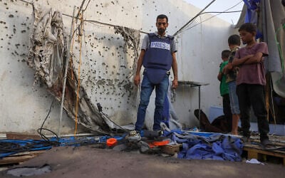 Palestinian children and a journalist examine the destroyed Al Jazeera tent at Al-Shifa Hospital in Gaza City on August 11, 2025, following an overnight strike by the IDF. (BASHAR TALEB / AFP)