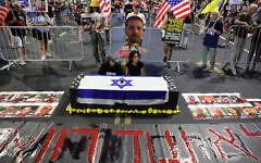 Enav Zangauker (R), mother of Israeli hostage Matan Zangauker, sits with a friend by a fake coffin during an anti-government protest calling for action to secure the release of Israeli hostages held captive since the Hamas-led October 7, 2023, attack in front of the defense ministry in Tel Aviv on August 12, 2025. (Jack GUEZ / AFP)