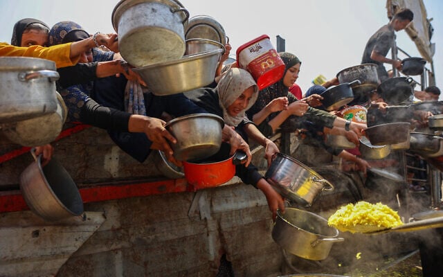 Palestinians gather to receive cooked meals from a food distribution center in Gaza City on August 13, 2025. (Photo by Omar AL-QATTAA / AFP) Palestinians gather to receive cooked meals from a food distribution center in Gaza City on August 13, 2025. (Photo by Omar AL-QATTAA / AFP)