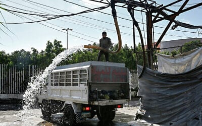 A man fills a tanker delivery truck with water from an underground water well distribution facility in Beirut on July 3, 2025. (Joseph EID / AFP)