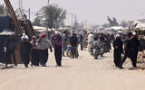 Palestinians carry humanitarian aid that they gathered after an aid drop, as they walk in the al-Mawasi area of Rafah in the southern Gaza Strip on August 18, 2025. (AFP)