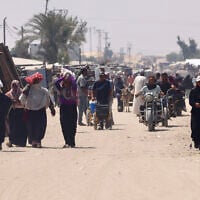 Palestinians carry humanitarian aid that they gathered after an aid drop, as they walk in the al-Mawasi area of Rafah in the southern Gaza Strip on August 18, 2025. (AFP)
