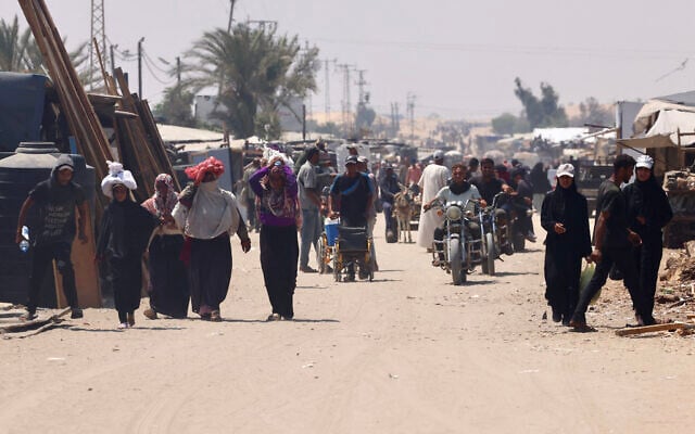 Palestinians carry humanitarian aid that they gathered after an aid drop, as they walk in the al-Mawasi area of Rafah in the southern Gaza Strip on August 18, 2025. (AFP) Palestinians carry humanitarian aid that they gathered after an aid drop, as they walk in the al-Mawasi area of Rafah in the southern Gaza Strip on August 18, 2025. (AFP)