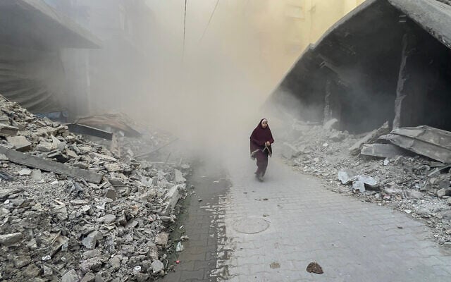 A Palestinian young woman rushes away from the site of Israeli airstrikes in the Saftawi neighborhood west of Jabalia in the northern Gaza Strip on August 19, 2025.  (Photo by Bashar TALEB / AFP)
