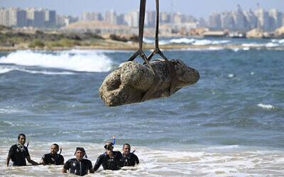 Divers watch as a crane pulls an artifact from the waters at Abu Qir Bay in Alexandria on August 21, 2025, during recovery of sunken antiquities. (Khaled Desouki / AFP)
