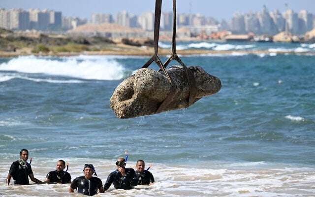 Divers watch as a crane pulls an artifact from the waters at Abu Qir Bay in Alexandria on August 21, 2025, during recovery of sunken antiquities. (Khaled Desouki / AFP)