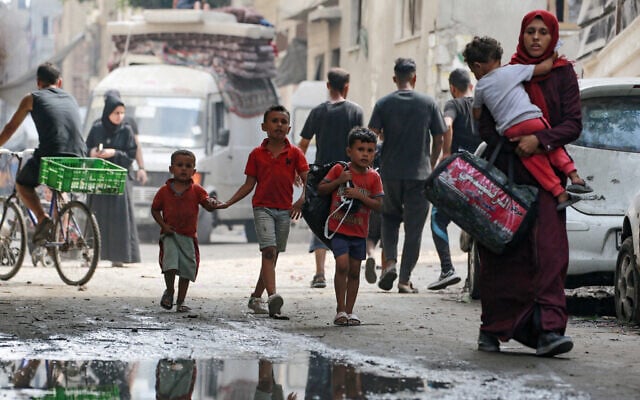 A Palestinian woman carries a child as she flees with others the Abu Iskandar neighborhood of northern Gaza City on August 22, 2025. (Bashar TALEB / AFP)