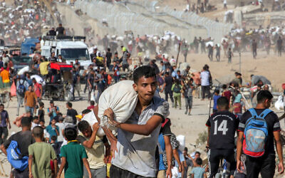 A youth walks with a sack on his shoulder with other people carrying bags of humanitarian aid they received at a distribution center run by the Gaza Humanitarian Foundation (GHF), in the central Gaza Strip, on August 22, 2025. (Eyad BABA / AFP)
