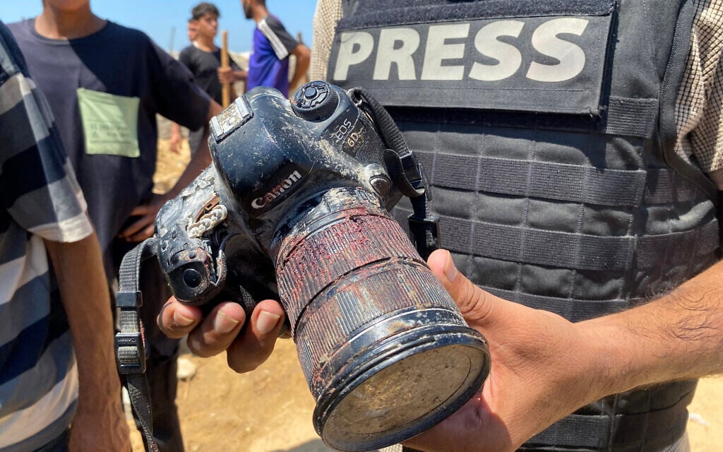 A journalist holds a blood-covered camera belonging to Palestinian photojournalist Mariam Dagga, a journalist who freelanced for AP who was killed in an Israeli strike on Nasser hospital in Khan Younis in the southern Gaza Strip, during her funeral on August 25, 2025. (AFP)