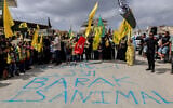 Protesters hold up Hezbollah flags behind graffiti reading 'Barak is animal,' as they demonstrate against the planned visit of US envoy Tom Barrack to south Lebanon, on August 27, 2025, in Khiam. (Rabih DAHER / AFP)