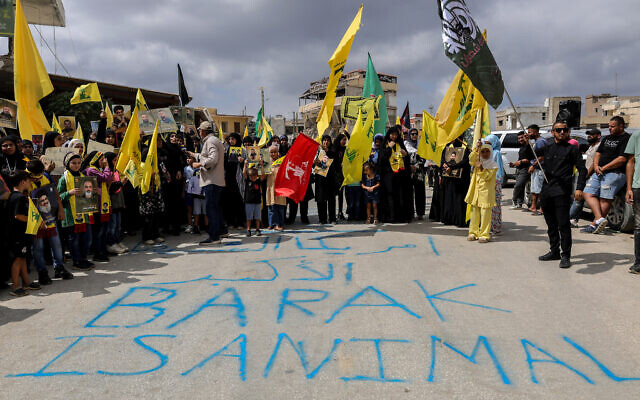 Protesters hold up Hezbollah flags behind graffiti reading 'Barak is animal,' as they demonstrate against the planned visit of US envoy Tom Barrack to south Lebanon, on August 27, 2025, in Khiam. (Rabih DAHER / AFP)