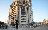 A Palestinian woman walks past a heavily damaged building in Gaza City on August 29, 2025. (BASHAR TALEB / AFP)