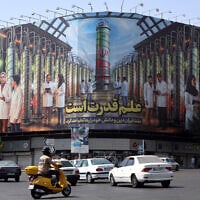 Iranians drive next to a billboard displaying pictures of nuclear scientists, centrifuges and a sentence reading in Farsi: 'Science is the power' at the Enqelab square in Tehran, on August 29, 2025 (AFP)