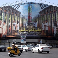 Illustrative: Iranians drive next to a billboard displaying pictures of nuclear scientists, centrifuges and a sentence reading 'Science is power' in Farsi, in Tehran, Iran, August 29, 2025. (AFP)
