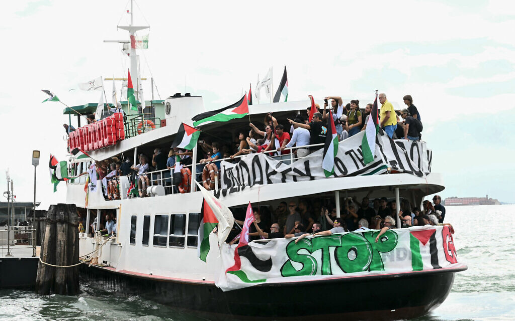 People aboard a boat wave Palestinian flags as they arrive to take part in a demonstration in support of Gaza at Venice Lido during the 82nd Venice International Film Festival, on August 30, 2025. (Photo by Stefano RELLANDINI / AFP)