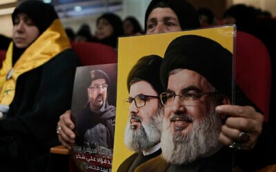 A woman holds photos of top Hezbollah commander Fouad Shukur, left, who was killed in an Israeli airstrike, Hezbollah's former leader Hassan Nasrallah, right, and his cousin and successor, Hashem Safieddine, center, during a commemoration marking the first anniversary of Shukur's death in Dahiyeh, a southern suburb of Beirut, Lebanon, July 30, 2025. (AP Photo/Bilal Hussein)