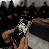 Haleema Ayyad, mother of slain Palestinian-American Khamis Ayyad, holds a mobile phone with her son's photo at the family house in Silwad, east of Ramallah, July 31, 2025. (AP/Nasser Nasser)