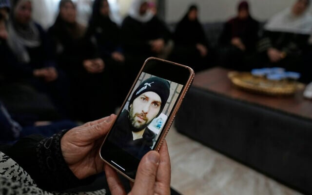 Haleema Ayyad, mother of slain Palestinian-American Khamis Ayyad, holds a mobile phone with her son's photo at the family house in Silwad, east of Ramallah, July 31, 2025. (AP/Nasser Nasser)
