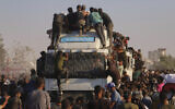 Palestinians ride on a truck loaded with food and humanitarian aid as it moves along the Morag corridor near Rafah, in the southern Gaza Strip, August 4, 2025. (AP/ Mariam Dagga)