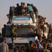 Palestinians ride on a truck loaded with food and humanitarian aid as it moves along the Morag corridor near Rafah, in the southern Gaza Strip, August 4, 2025. (AP/ Mariam Dagga)