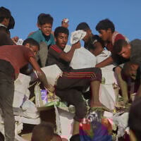 Palestinians struggle to get food and humanitarian aid from the back of a truck as it moves along the Morag corridor near Rafah, in the southern Gaza Strip, August 4, 2025. (AP Photo/ Mariam Dagga)